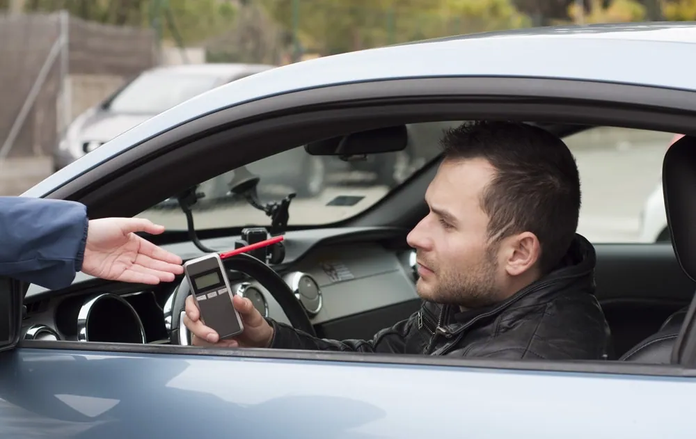 Police officer giving breathalyzer test to the drunk driver.