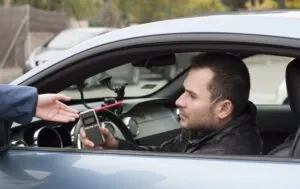Police officer giving breathalyzer test to the drunk driver.